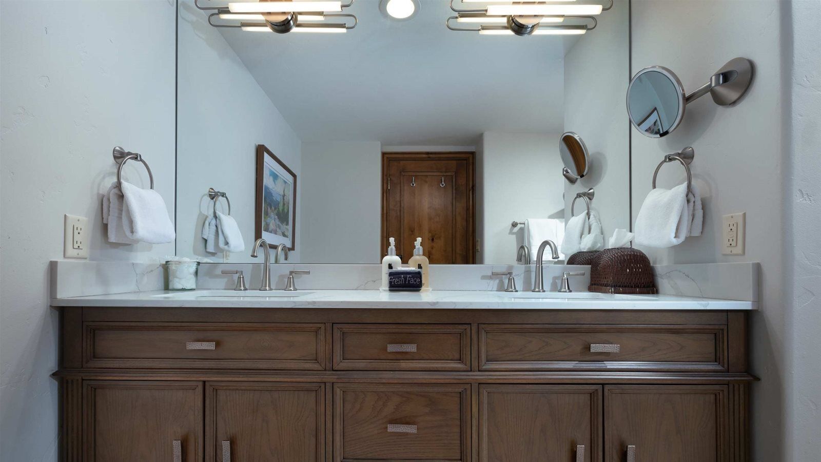 Une salle de bain avec un meuble-lavabo à deux vasques, un miroir et un meuble en bois doté de tiroirs.