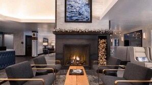 Ein moderner Lounge-Bereich mit Kamin, bequemen Sitzmöglichkeiten und einem großen Gemälde an der Wand.