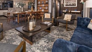 Un moderno vestíbulo de hotel con zona de comedor, asientos y estantería.