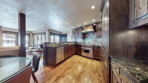A spacious kitchen with wooden cabinets, a large island, and a stone backsplash. - Snowmass_village_3bd_gen_c (Snowmass Village)