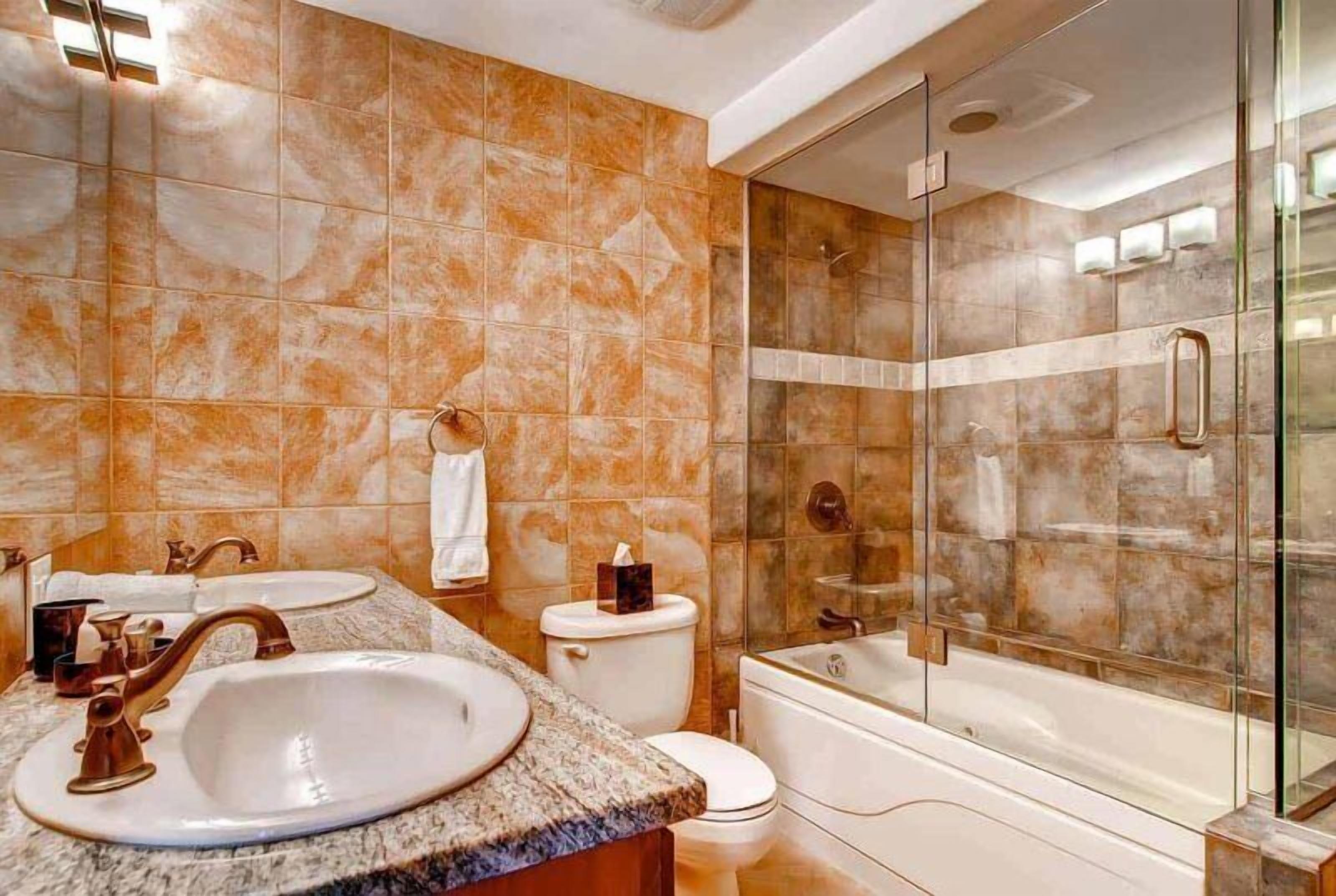 A bathroom with two sinks, a toilet, a bathtub, and a glass-enclosed shower.