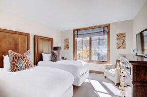 Une chambre d’hôtel avec deux lits, une commode, une télévision et une fenêtre donnant sur les arbres.