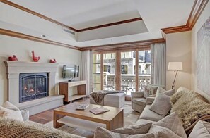 A spacious living room with a fireplace, comfortable seating, and a view of the outside balcony. - Vail Ritz-carlton 3 Bedroom Residence (Vail)