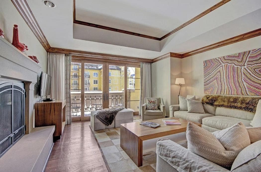 A hotel room with a balcony, a sofa, a coffee table, and a TV.