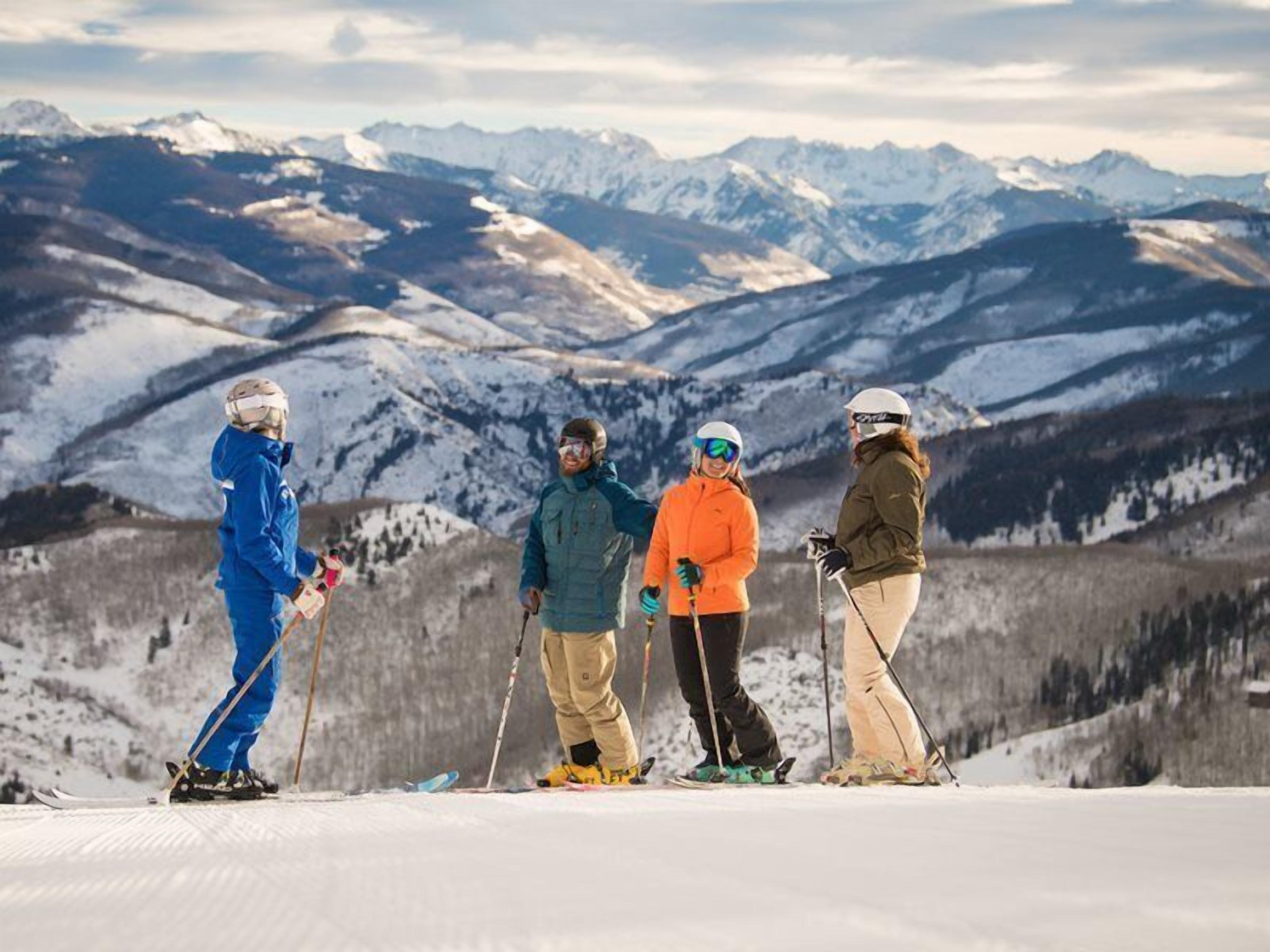 A group of skiers on a snowy mountain with a backdrop of snow-covered peaks.