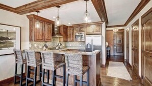 A spacious kitchen with wooden cabinets, a large island with bar stools, and modern appliances. - Vail Ritz-carlton 2 Bedroom Residence (Vail)