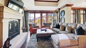 A spacious living room with a fireplace, comfortable seating, and large windows offering a view of the outdoors. - Vail Ritz-carlton 2 Bedroom Residence (Vail)
