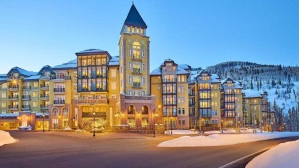 A multi-story hotel with a prominent tower, snow-covered surroundings, and a well-lit entrance. - Vail Ritz-carlton 2 Bedroom Residence (Vail)