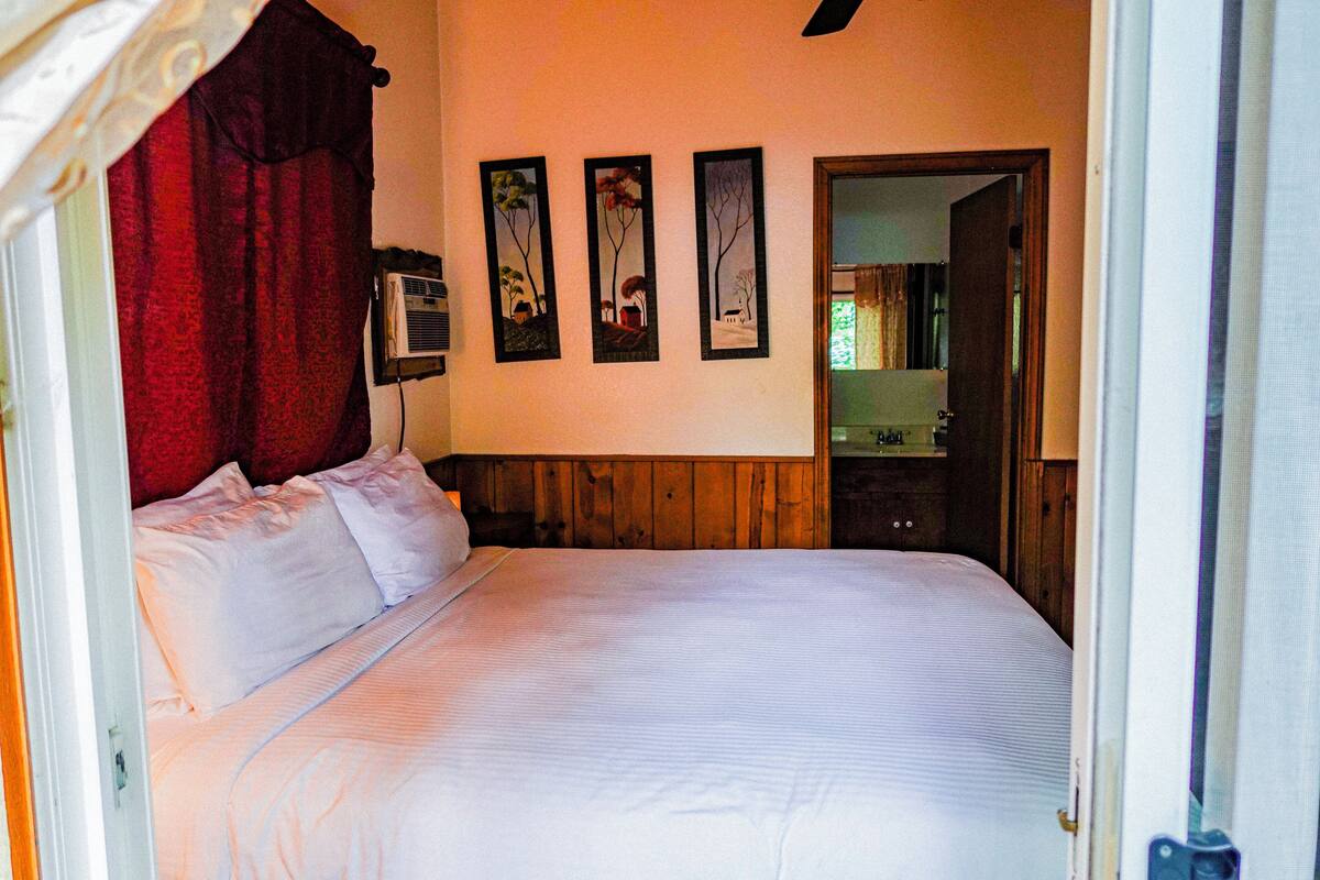 Ein Schlafzimmer mit einem großen Bett, einem hölzernen Kopfteil und drei gerahmten Bildern an der Wand.