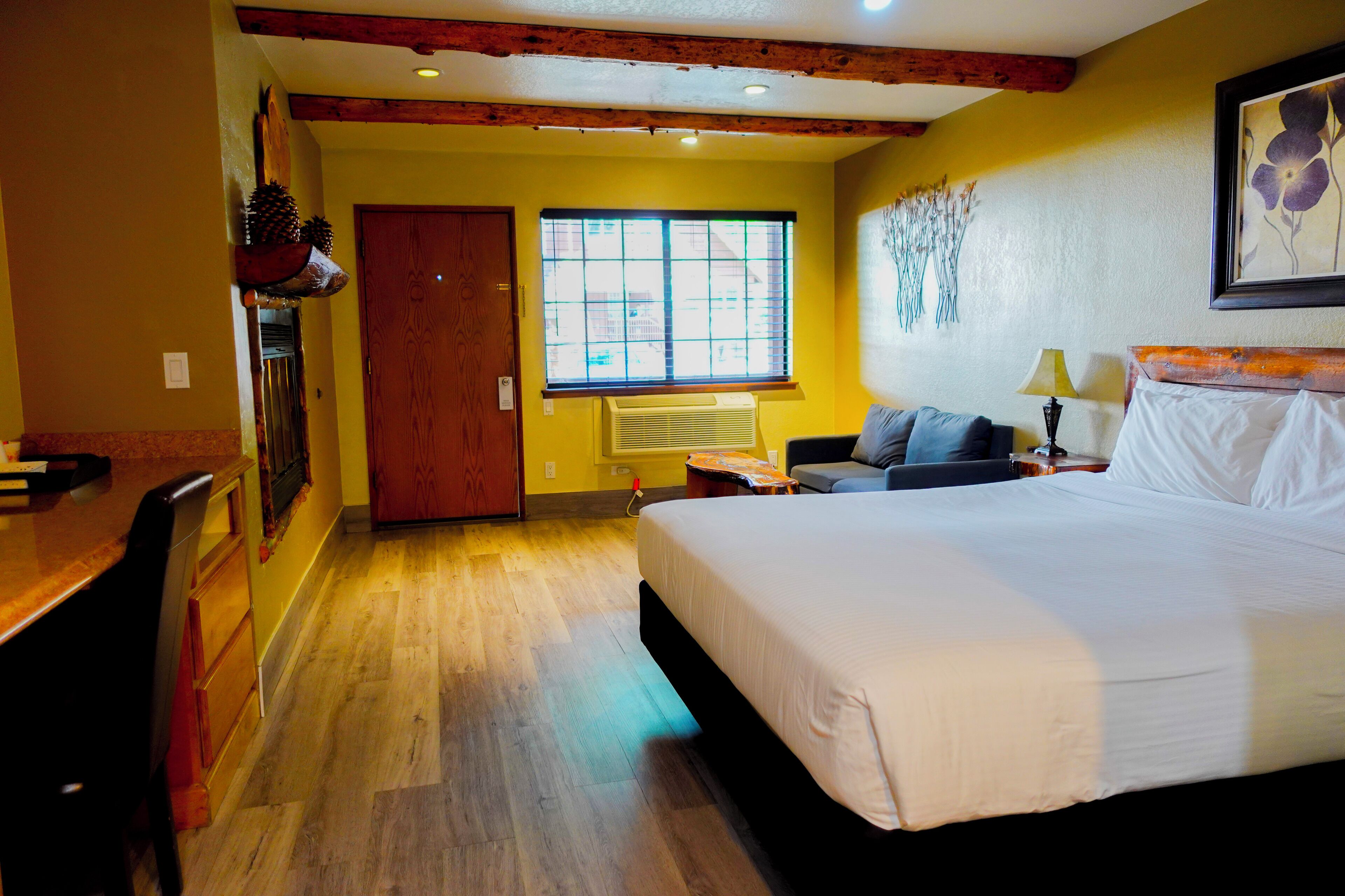 Une chambre d’hôtel avec un grand lit, un bureau et une fenêtre avec des stores.