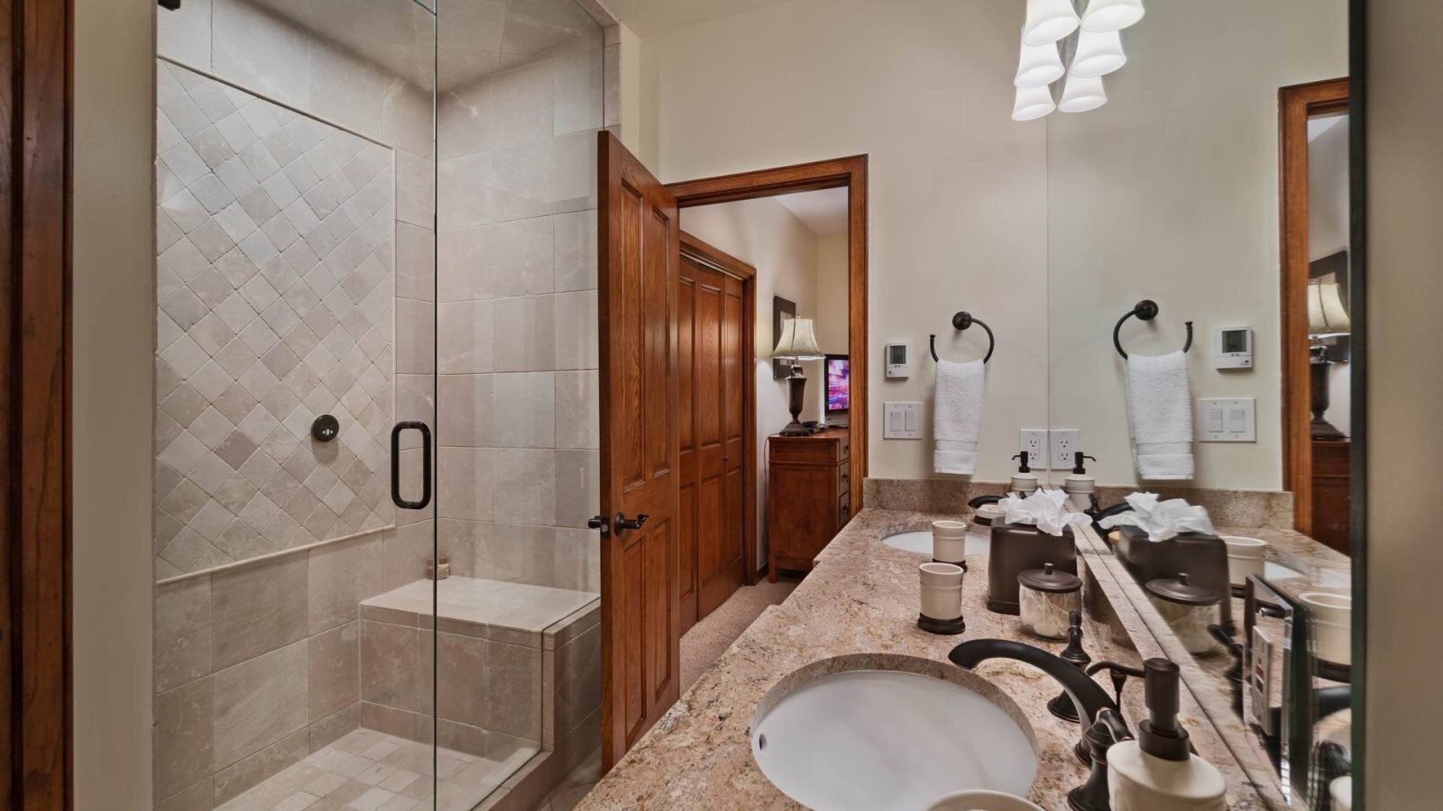 A modern bathroom with a glass-enclosed shower, a vanity with a sink, and a mirror.