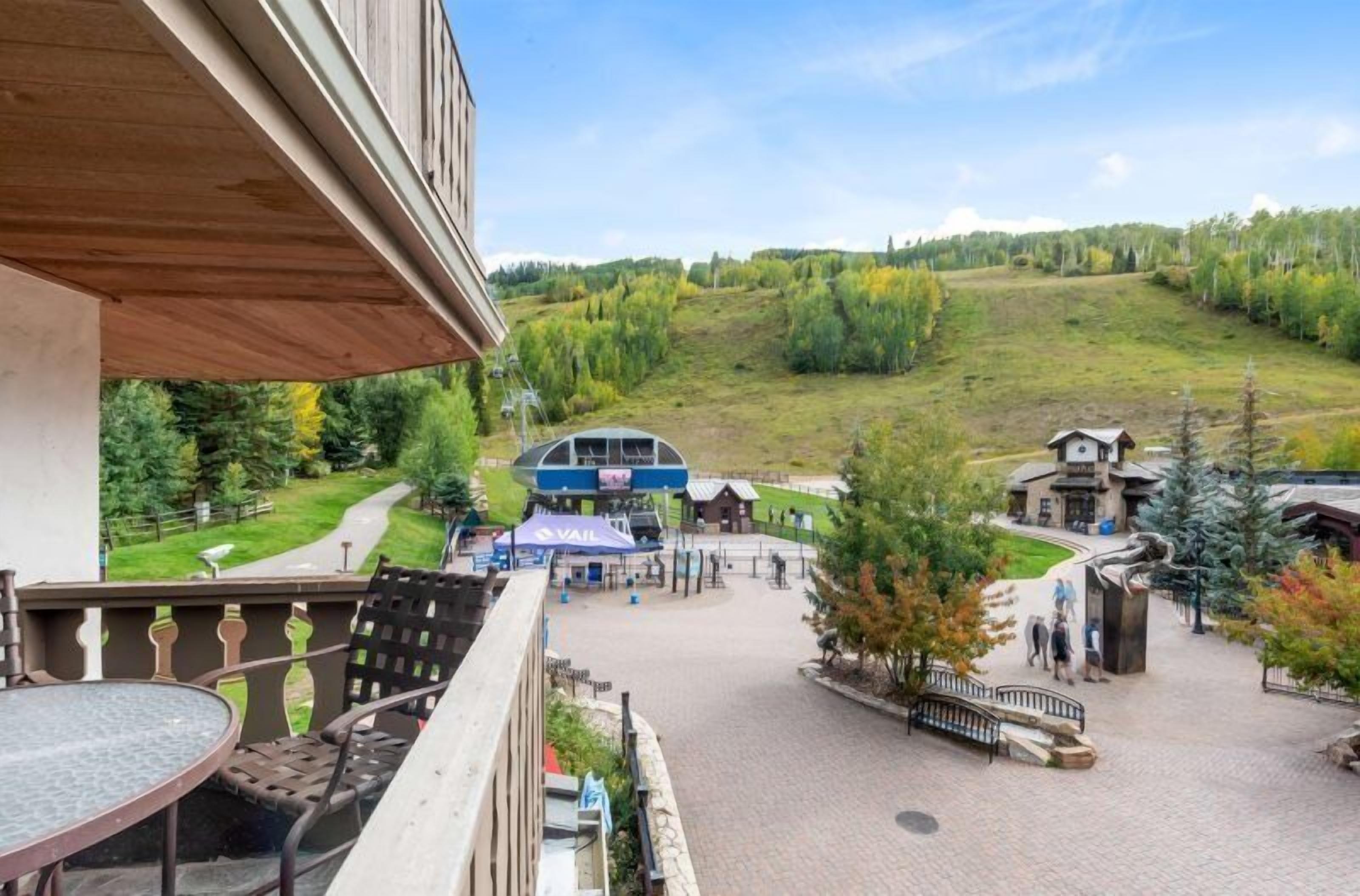 A hotel with a balcony overlooking a parking area and a hilly landscape.