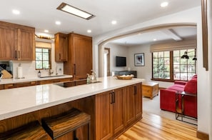 Una cocina moderna con armarios de madera, una isla grande y un sofá rojo en el área de estar contigua.