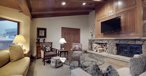 Relax in this inviting living room with a comfortable sofa set, stone fireplace, and mounted TV.
