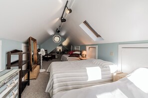 Relax in this charming attic bedroom with a large bed, wooden wardrobe, and desk area.