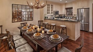 A dining area with a wooden table set for a meal, surrounded by cushioned chairs. - Beaver_creek_chalet_fortessa (Avon)