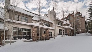 A snow-covered residential area with multiple houses, a stone facade, and a clear sky. - Beaver_creek_chalet_fortessa (Avon)