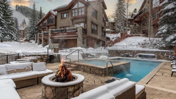 En resort med opvarmet udendørs pool, pejs af sten og sneklædte omgivelser.