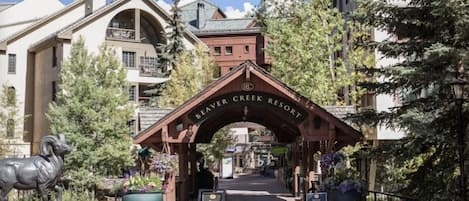 The entrance to Beaver Creek Resort with a wooden archway, a signboard, and a statue of a ram.