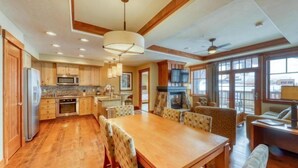 A spacious kitchen with wooden cabinets, a granite countertop, and a dining area with a large table and chairs. - One Ski Hill Place 2 Bedroom Luxury Condo (Breckenridge)