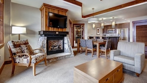 A spacious living room with a fireplace, a dining area, and a kitchen. - One Ski Hill Place 2 Bedroom Luxury Condo (Breckenridge)