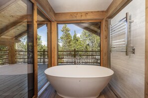 A modern bathroom with a freestanding bathtub, large windows, and a wooden deck. - Breck_le_mayen _6bd (Breckenridge)