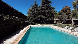 Una piscina rettangolare con acqua cristallina, circondata da un solarium in pietra e una recinzione in metallo.