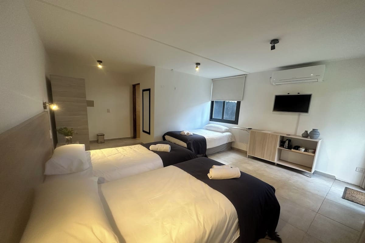 A hotel room with two beds, a desk, a TV, and a window.