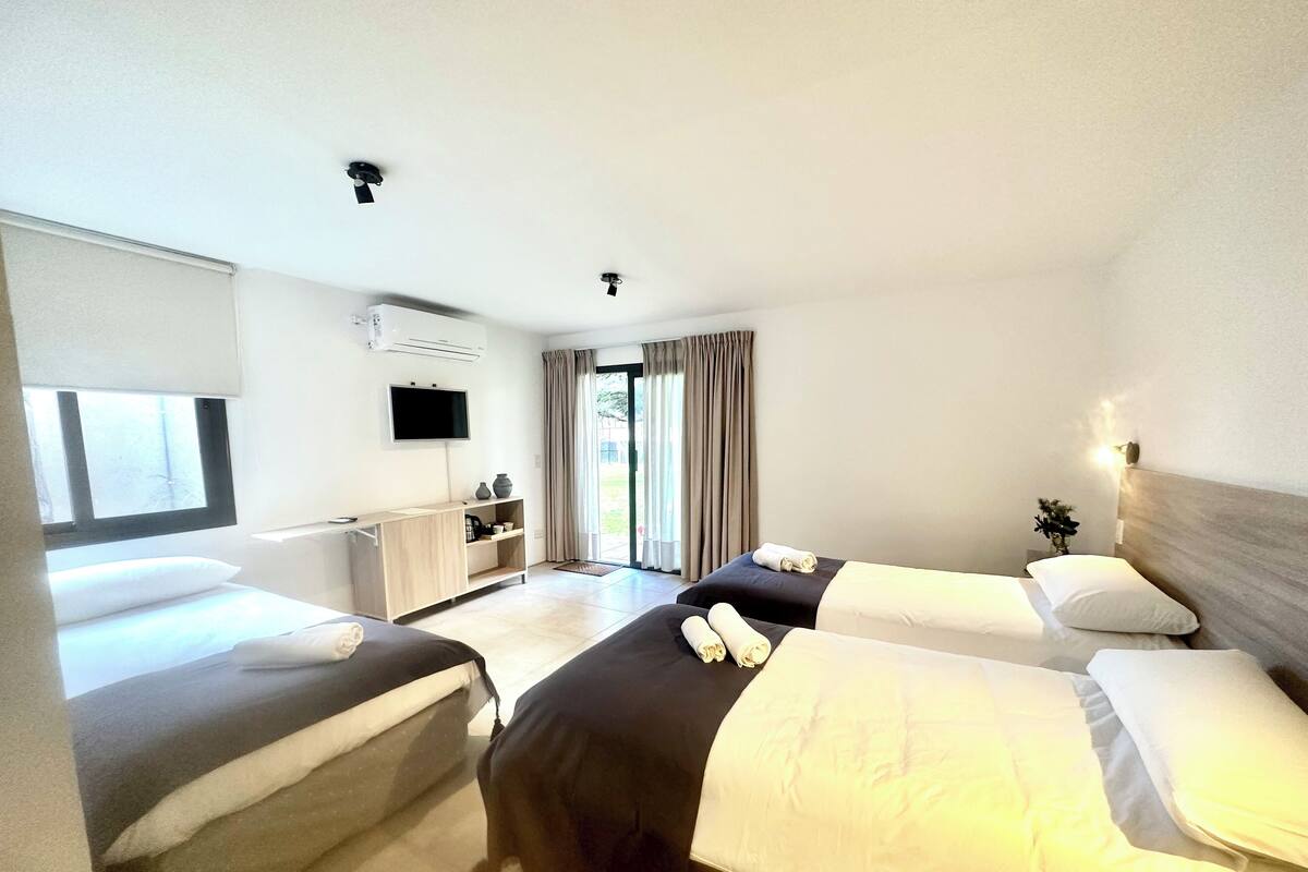 A hotel room with two beds, a TV, a desk, and a window.