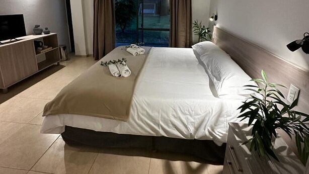 Una camera d'albergo con un letto, una televisione, una scrivania e una finestra con tende.