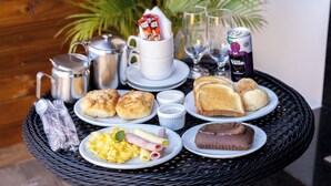 A breakfast buffet with various food items and beverages on a wicker table. - Medieval Motel SPA (Porto Alegre)