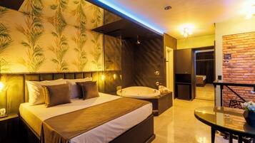 A modern hotel room with a large bed, a separate bathroom, a sitting area with a table, and a brick wall.