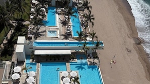 A resort with multiple swimming pools, palm trees, and a beach.