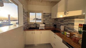 Una cucina compatta con vista sul mare, una finestra e un soffitto in legno.