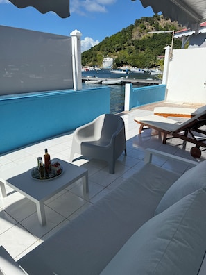 A sunlit outdoor seating area with a table, chairs, and lounge chairs. - KAZPARADIS LES SAINTES  (Terre-de-Haut)