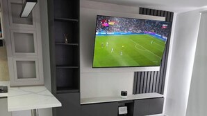 Ein modernes Wohnzimmer mit Flachbildfernseher an der Wand, Marmorboden und eingebauten Regalen.