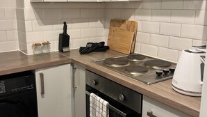 Una cucina con fornello, bollitore e tagliere.