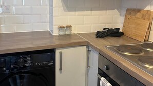 Una cucina compatta con lavastoviglie, forno e piano cottura.