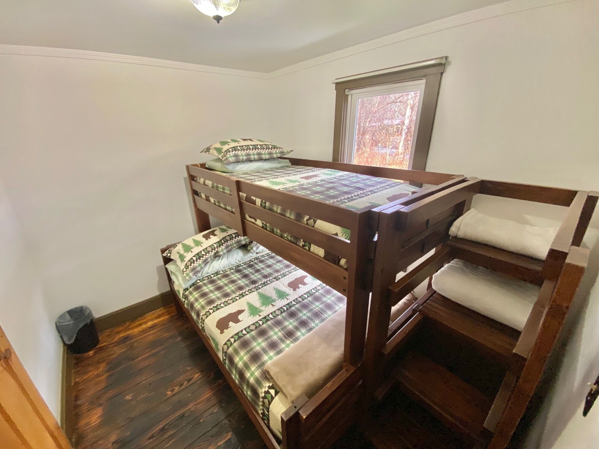 A bunk bed room with a window and a ceiling light.