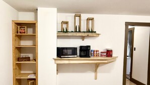 Une cuisine équipée d  ’étagères en bois, d’un four à micro-ondes, d’une machine à café et de boissons en conserve.