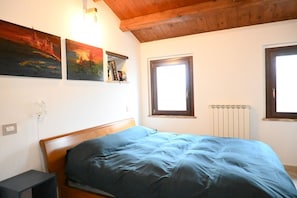 A bedroom with a bed, a window, a radiator, and wall-mounted artwork.