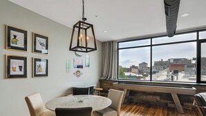 Een moderne eetruimte met een ronde tafel, stoelen en een groot raam met uitzicht over de stad.
