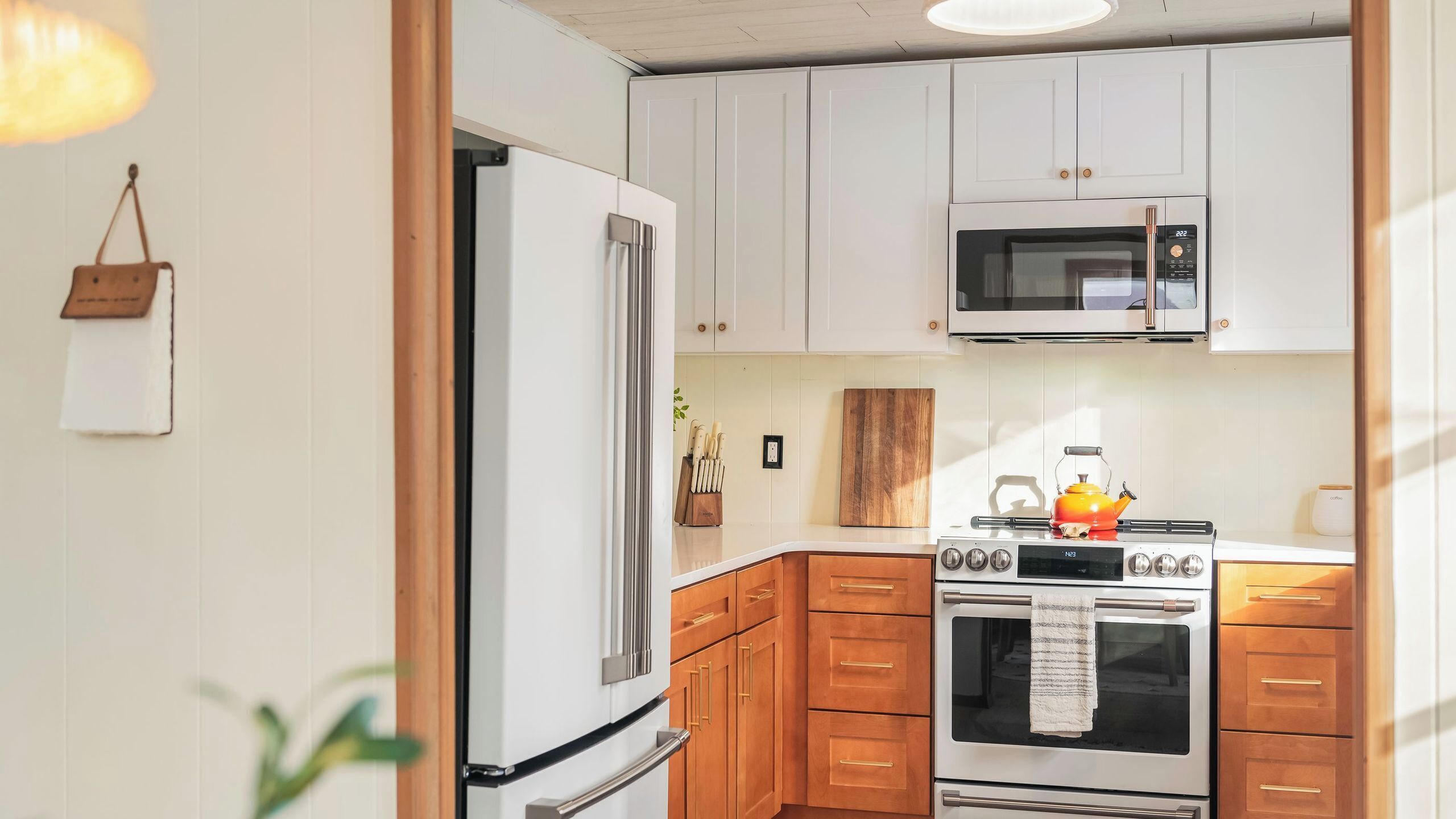 A kitchen with white cabinets, a stainless steel refrigerator, a microwave, and an oven.