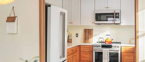A kitchen with white cabinets, a stainless steel refrigerator, a microwave, and an oven.