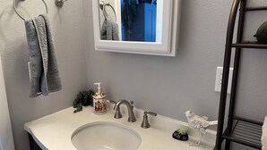 Une salle de bain avec un lavabo, un miroir et un porte-serviettes.