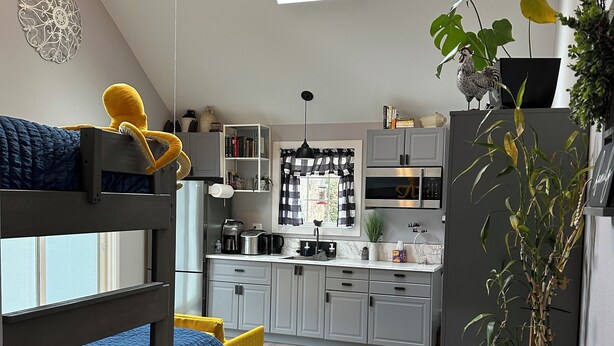 Un appartement moderne et compact, avec une chambre à l’aménagement de type « loft », comprenant un lit superposé, une kitchenette avec un coin repas et une lucarne.