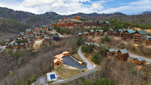 A lodge with multiple wooden cabins, a swimming pool, and a winding road. - Anne's Place by Avantstay Cozy Cabin With Hot Tub, Games, Near Dollywood Attractions (Sevierville)