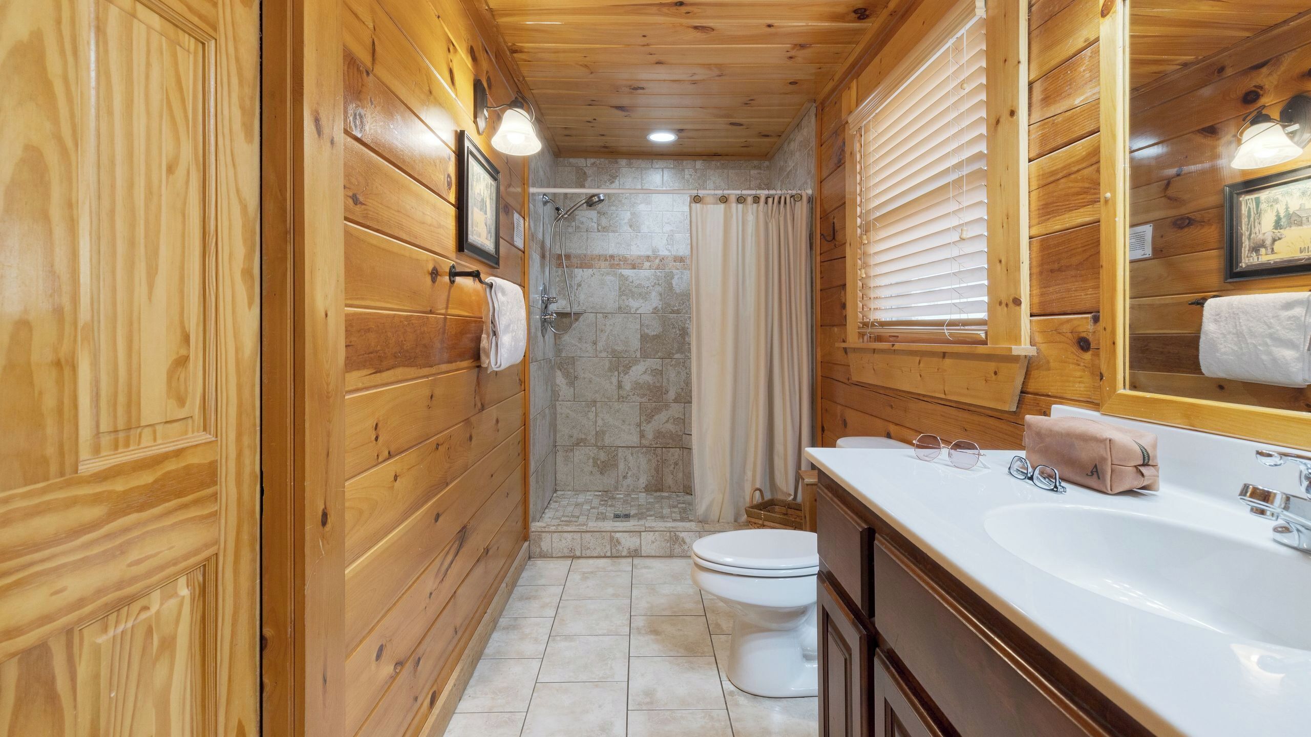Un bagno in legno con doccia, wc, lavandino e specchio.