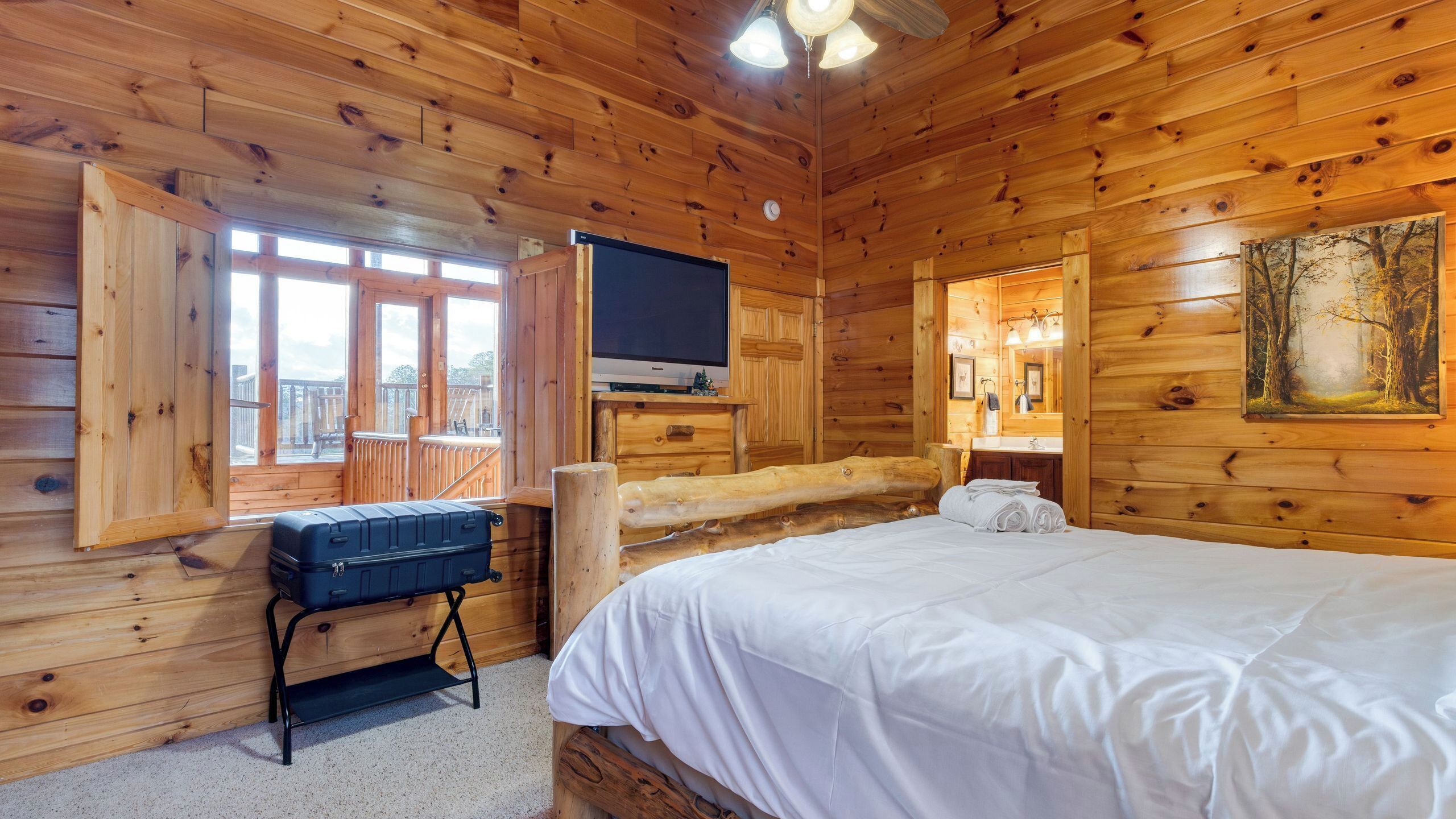 A wooden cabin room with a bed, a TV, and a balcony.