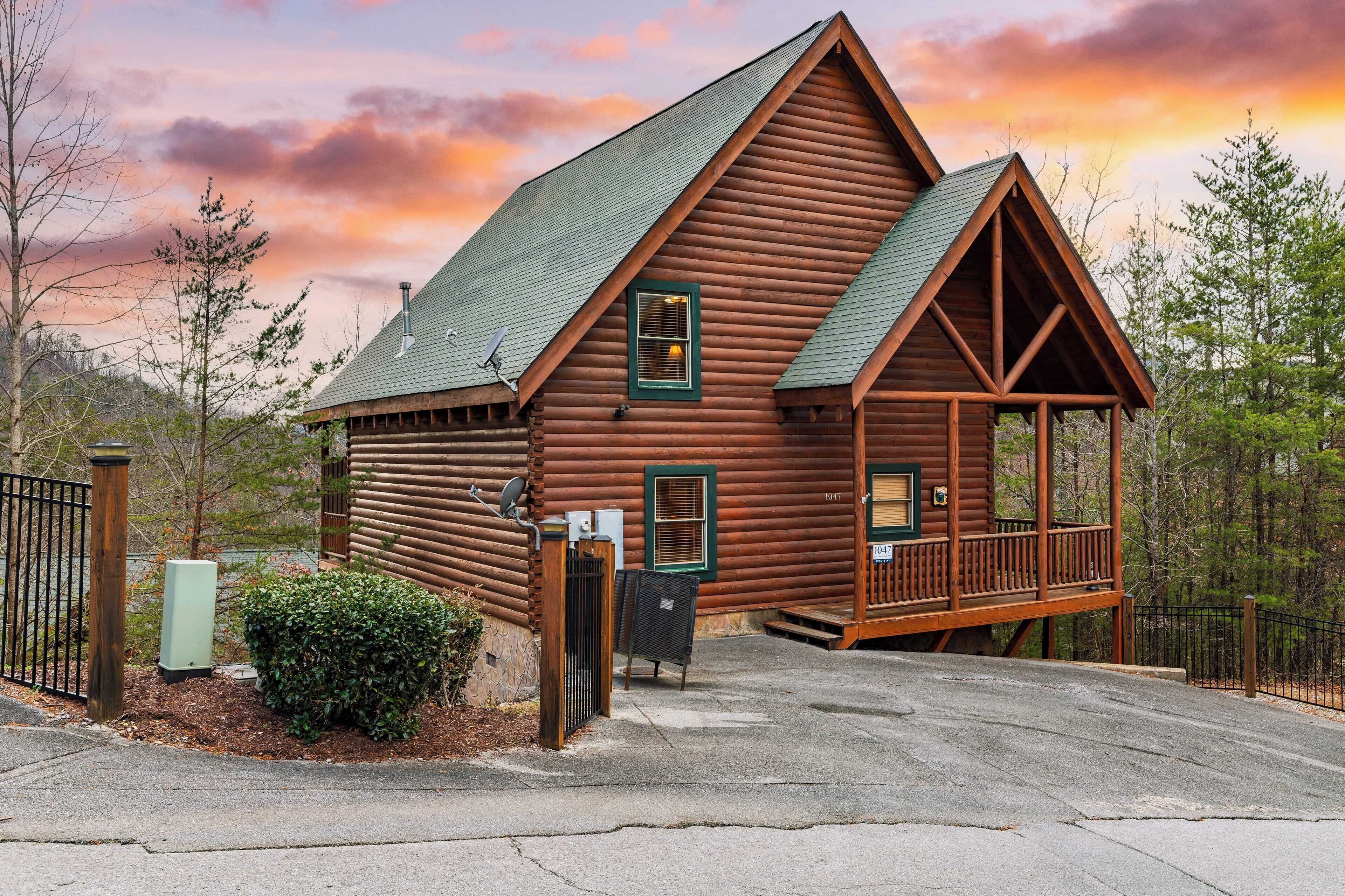 A log cabin with a porch, a green roof, and a small window.